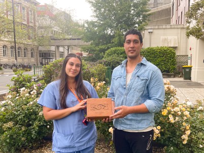 Two young Māori doctors holding an engraved box